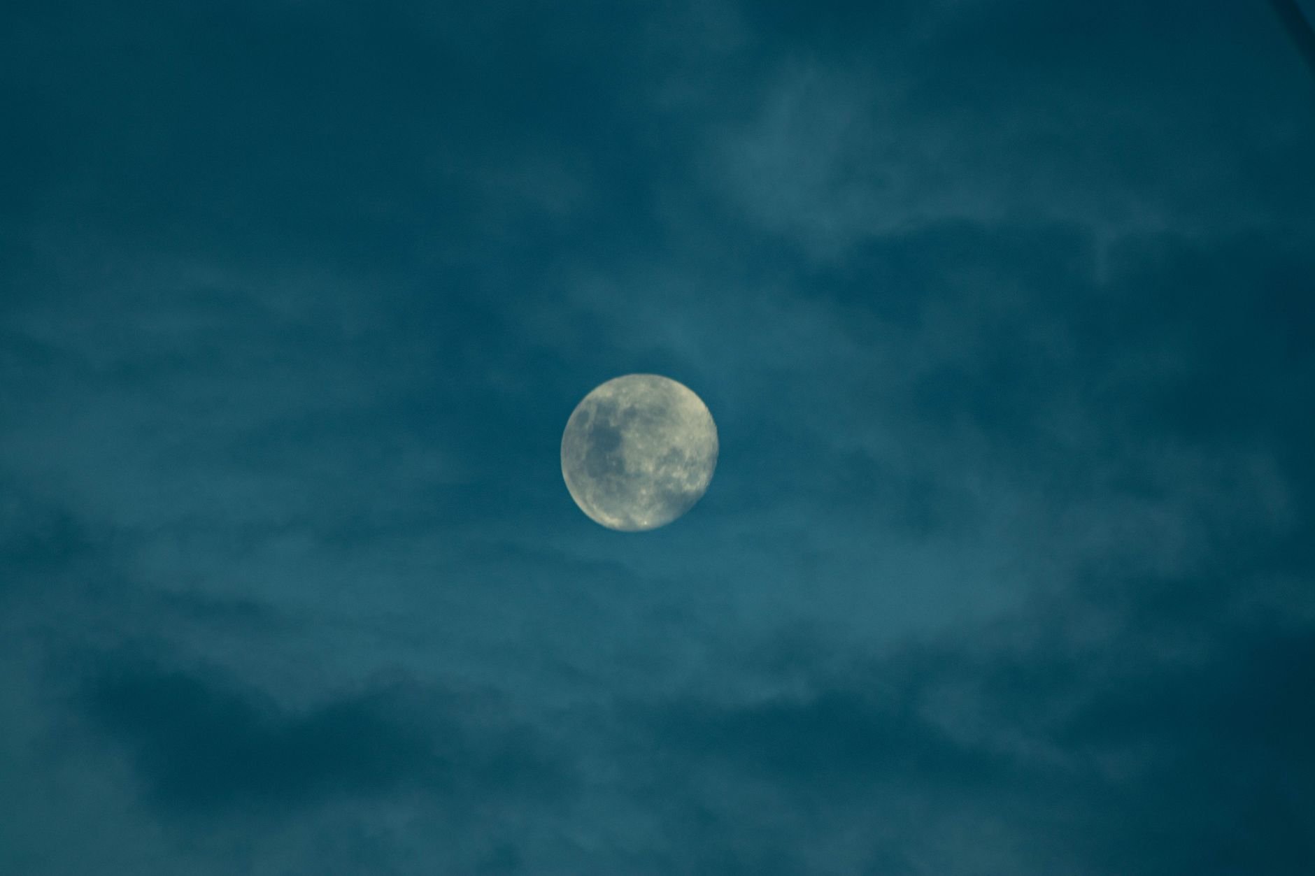 A full moon shining through a cloudy night sky, creating a serene and mystical atmosphere.